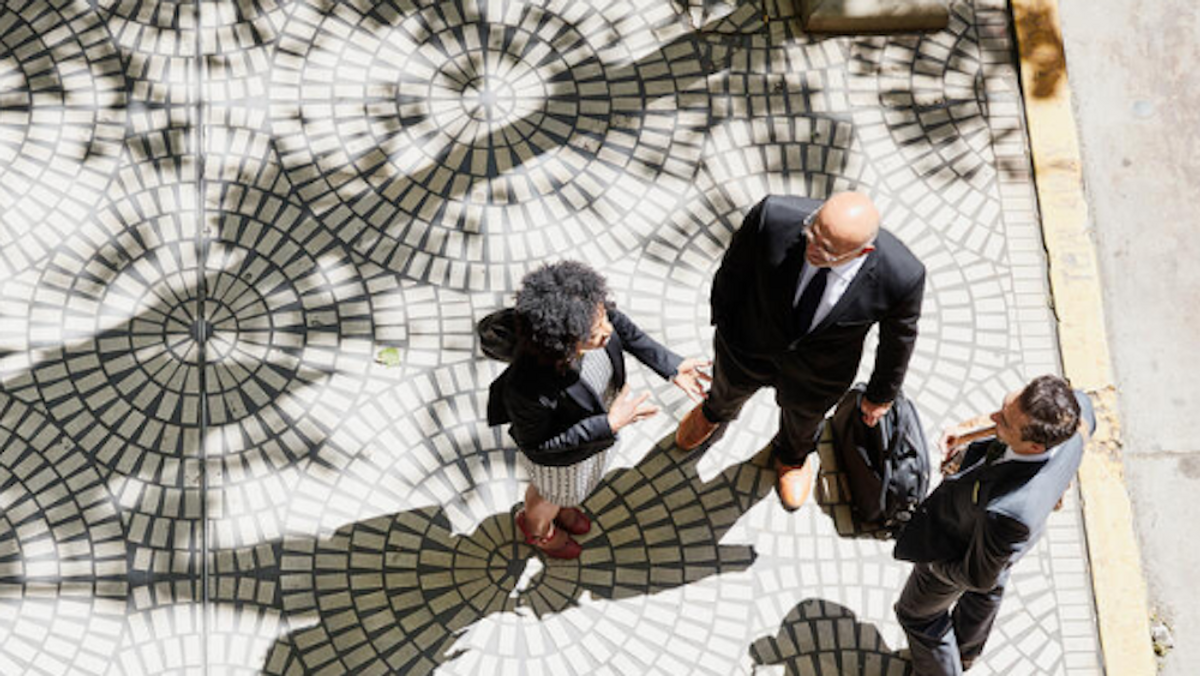 3 people in business attire in the street speaking