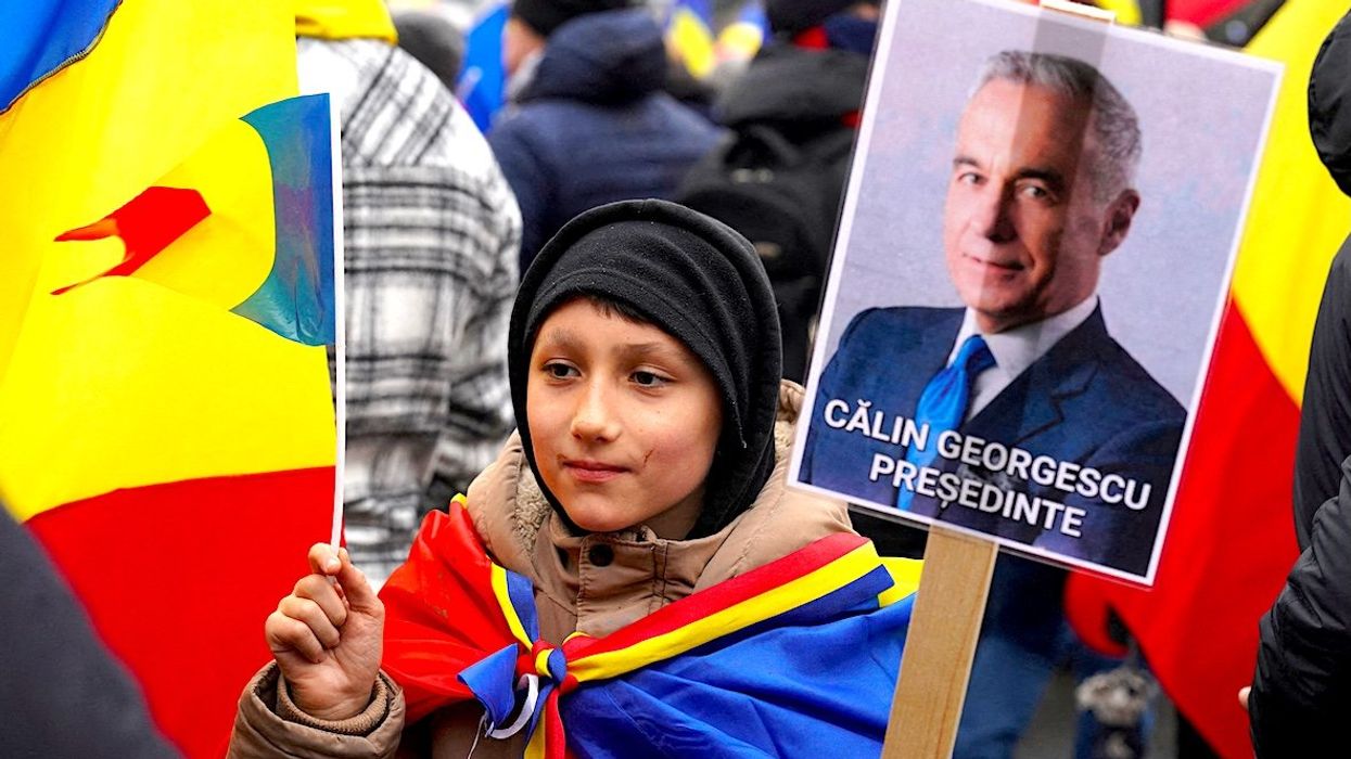 A boy holds a sign reading "Calin Georgescu President" during an anti-government rally in Bucharest, Romania.