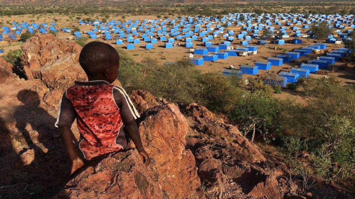A boy sits atop a hill overlooking a refugee camp near the Chad-Sudan border, November 9, 2023. Hundreds of Masalit families from Sudan's West Darfur state were relocated here months after fleeing to the Chadian border town of Adre, following an ethnically targeted massacre in the city of El Geneina.