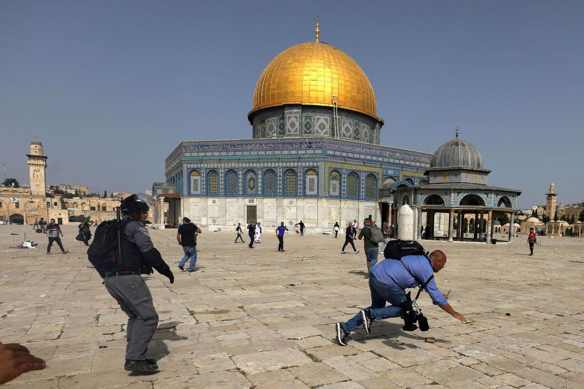 A camera operator falls as an Israeli police officer runs after him during clashes with Palestinians at the compound that houses Al-Aqsa Mosque, known to Muslims as Noble Sanctuary and to Jews as Temple Mount, in Jerusalem's Old City, May 10, 2021