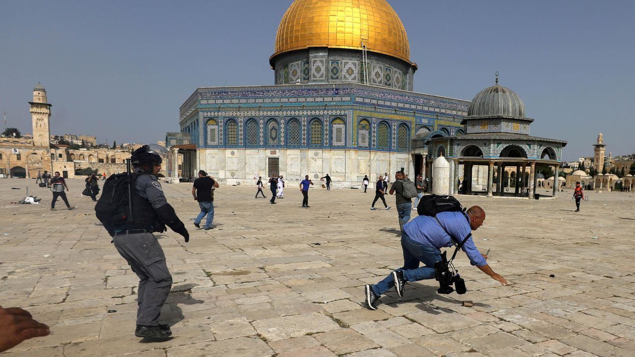 A camera operator falls as an Israeli police officer runs after him during clashes with Palestinians at the compound that houses Al-Aqsa Mosque, known to Muslims as Noble Sanctuary and to Jews as Temple Mount, in Jerusalem's Old City, May 10, 2021