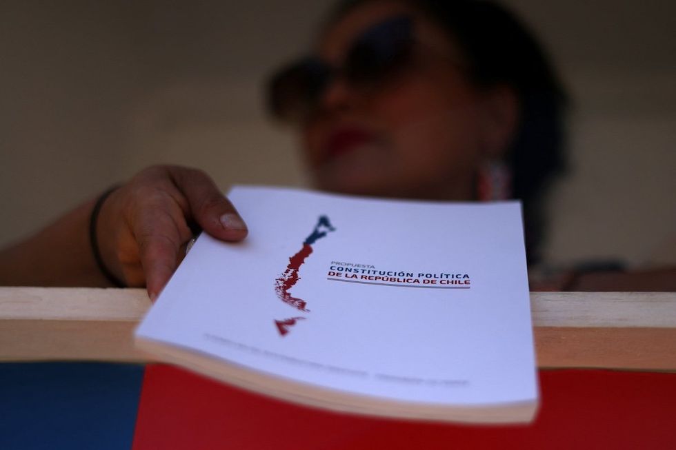 A citizen delivers copies of the proposed new Chilean constitution ahead of the upcoming December 17 constitutional referendum, outside the government palace in Santiago, Chile November 27, 2023.