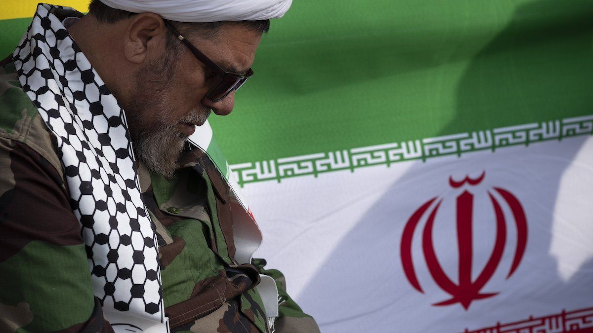 A cleric who supports the Islamic Republic and the Supreme Leader Ayatollah Ali Khamenei is sitting next to an Iranian flag during a rally to mark the 45th anniversary of the victory of Iran's 1979 Islamic Revolution on Azadi (Freedom) Avenue in western Tehran, Iran, on February 11, 2024.