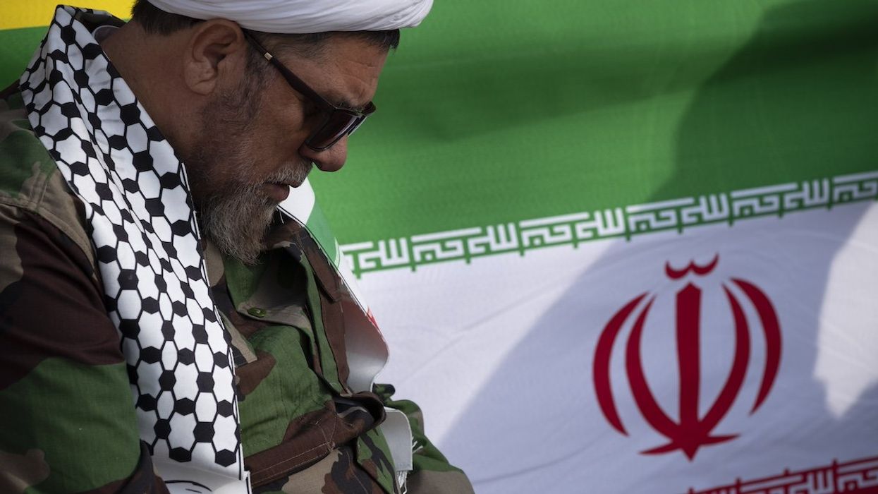 A cleric who supports the Islamic Republic and the Supreme Leader Ayatollah Ali Khamenei is sitting next to an Iranian flag during a rally to mark the 45th anniversary of the victory of Iran's 1979 Islamic Revolution on Azadi (Freedom) Avenue in western Tehran, Iran, on February 11, 2024.
