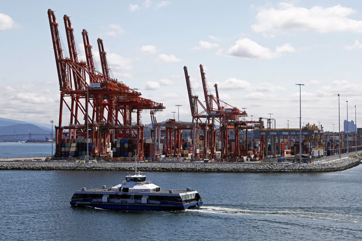 A commuter Seabus passes idle shipping cranes towering over stacked containers during a strike by dock workers at Canada's busiest port of Vancouver, British Columbia.