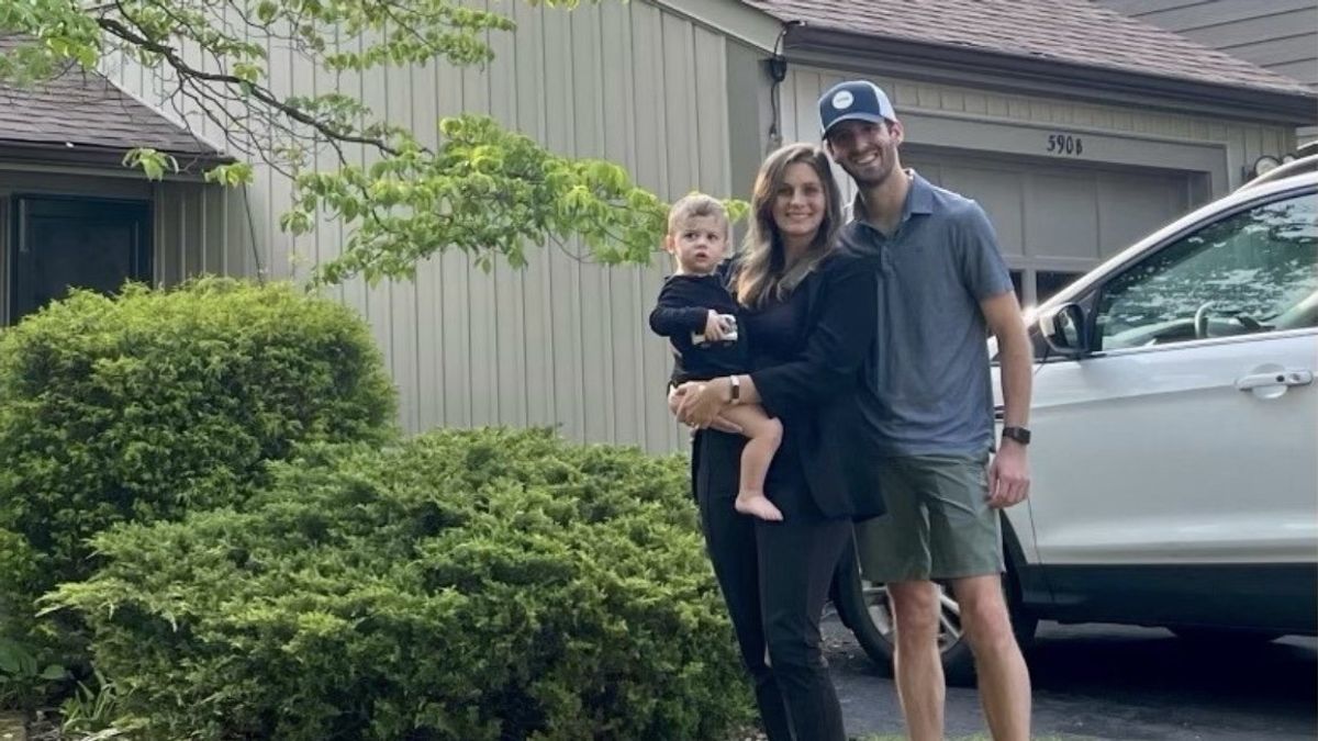 A couple with their child in standing front of their house