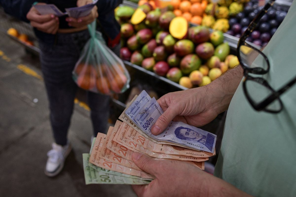 A customer counts Venezuelan Bolivar notes at a stall in a municipal market in Caracas, Venezuela. 
