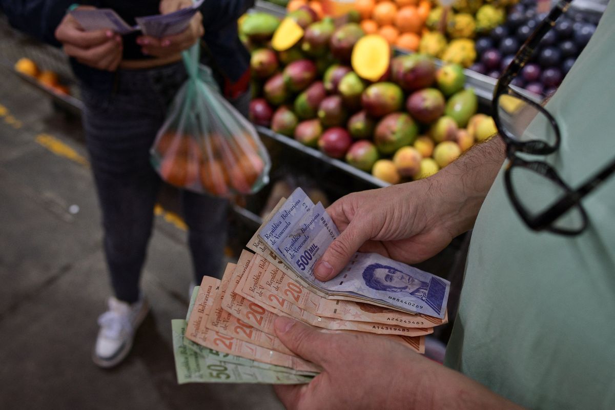A customer counts Venezuelan Bolivar notes at a stall in a municipal market in Caracas, Venezuela.