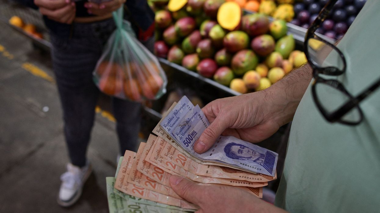A customer counts Venezuelan Bolivar notes at a stall in a municipal market in Caracas, Venezuela.