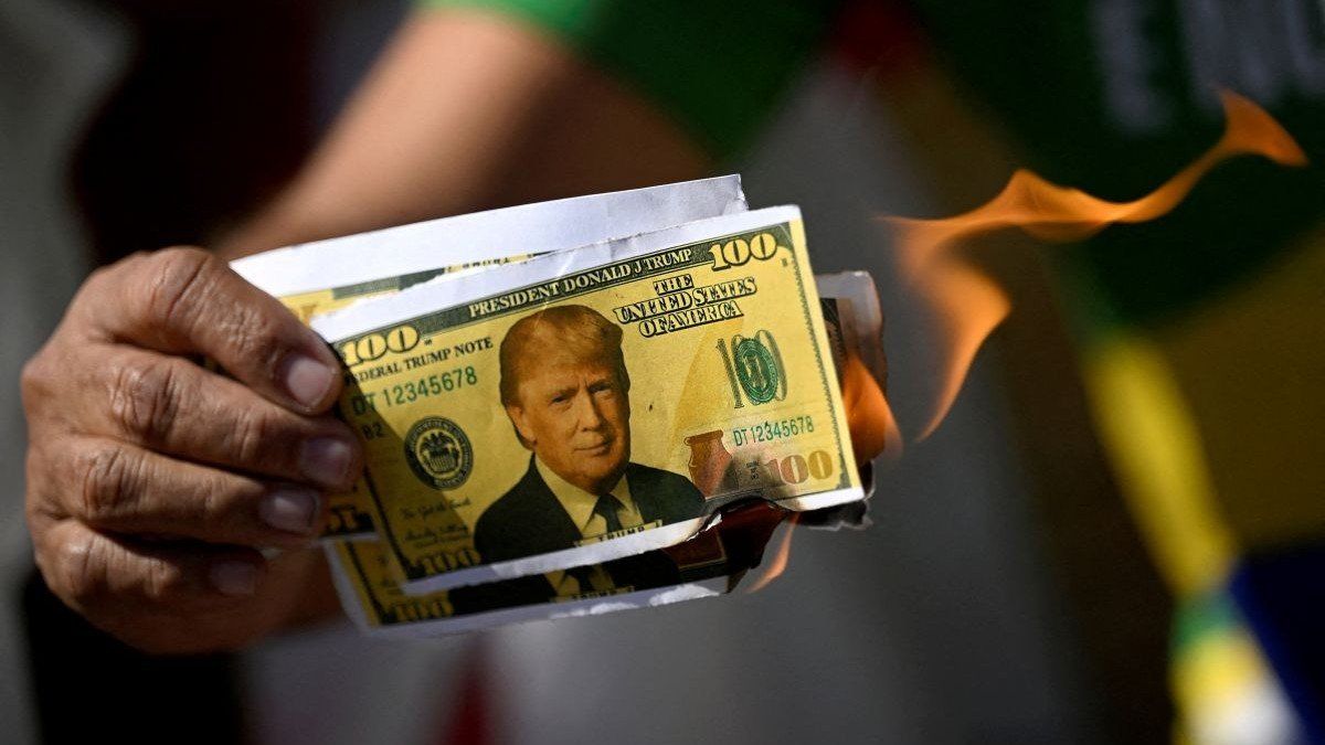​A demonstrator burns mock dollar bills in front of the United States Embassy in Brasilia, Brazil, on August 1, 2025.