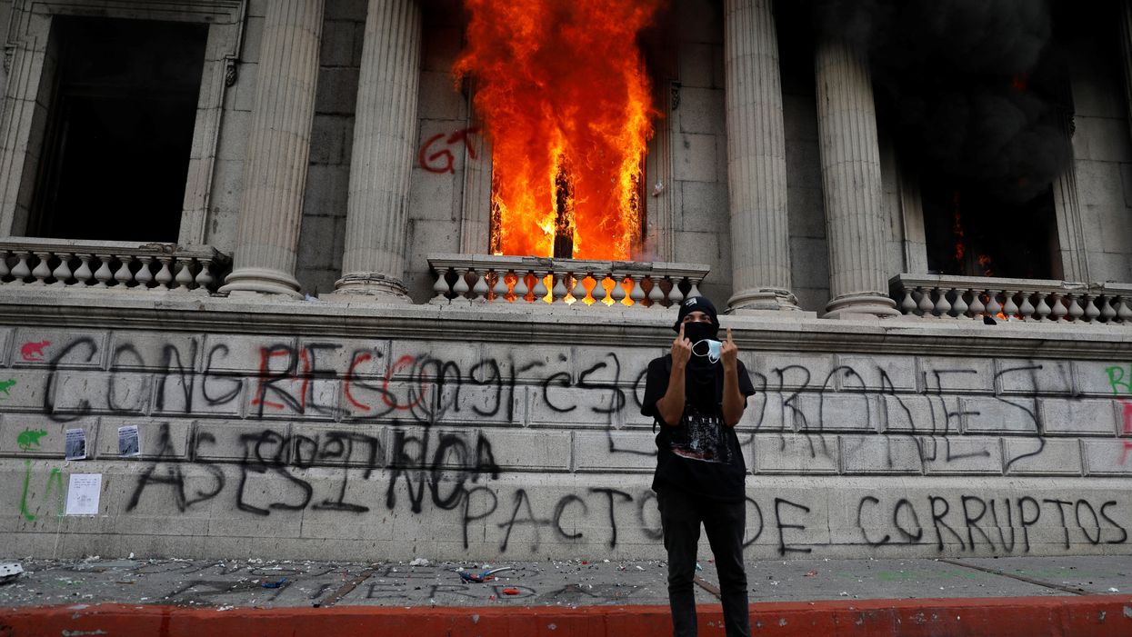A demonstrator gestures after demonstrators set an office of the Congress building on fire during a protest demanding the resignation of President Alejandro Giammattei, in Guatemala City, Guatemala November 21, 2020.