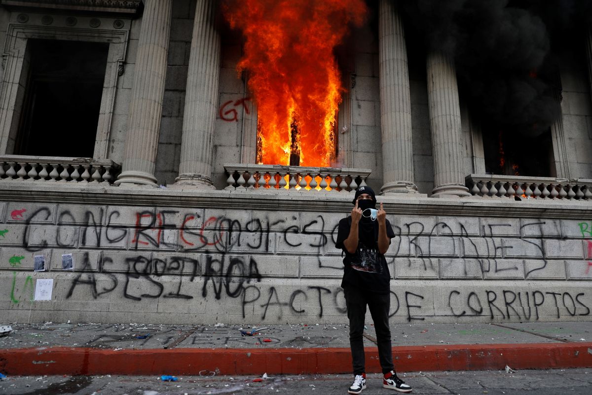 A demonstrator gestures after demonstrators set an office of the Congress building on fire during a protest demanding the resignation of President Alejandro Giammattei, in Guatemala City, Guatemala November 21, 2020.