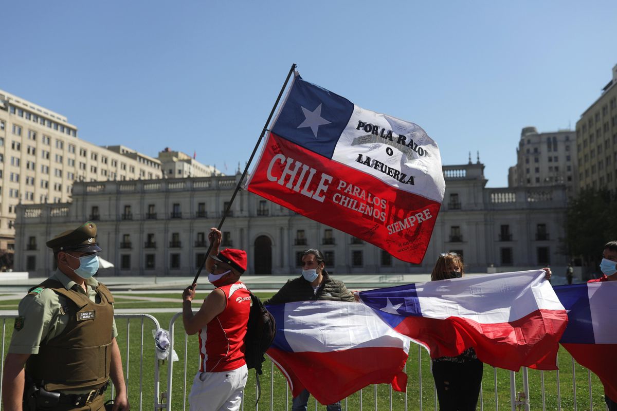A demonstrator hold a Chile's flag that reads: "Chile for Chileans always, By reason or the force", in front of a government palace during an anti-immigration protests in Santiago, Chile, October 2, 2021