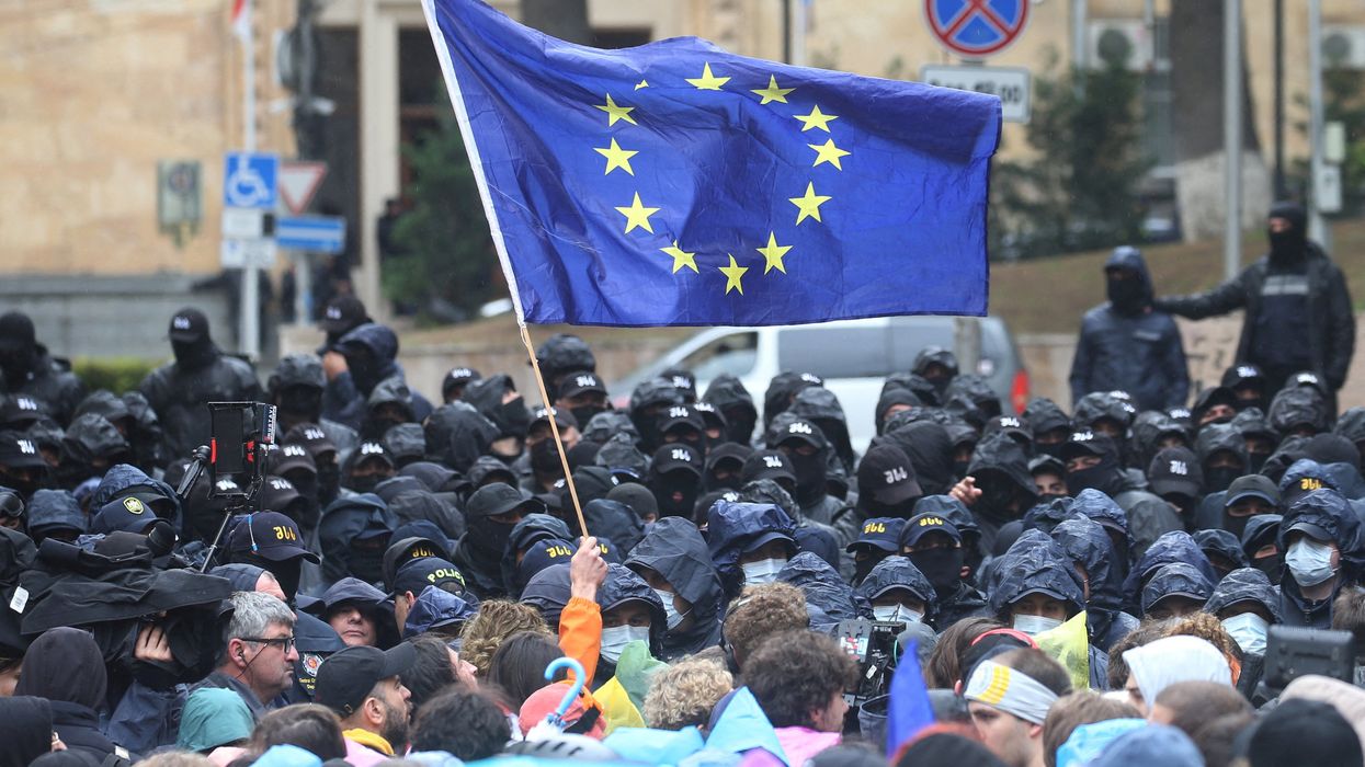 A demonstrator holds a European Union flag in front of law enforcement officers during a rally to protest against a bill on "foreign agents" in Tbilisi, Georgia, May 14, 2024.