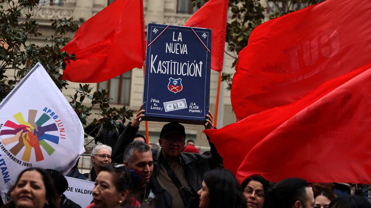 A demonstrator holds up a model depicting a Chilean constitution book that reads 'The new Kastitucion' in a play on the word 'Constitution' and the name of far right-wing politician Jose Antonio Kast, while protesting against ongoing Constitutional process lead by right-wing parties, in Santiago, Chile, October 3, 2023.