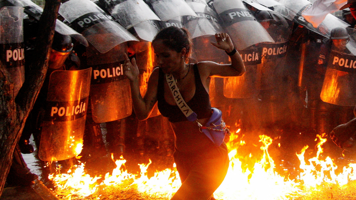 A demonstrator reacts when Molotov cocktails hit the ground in front of security forces during protests against election results after Venezuela's President Nicolas Maduro claimed victory in Sunday's presidential election, in Puerto La Cruz, Venezuela. 