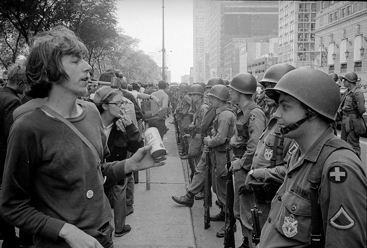 ​A demonstrator stands in front of a row of National Guard soldiers, across the street from the Hilton Hotel in Grant Park, site of the Democratic National Convention in Chicago, Illinois, on Aug. 26, 1968.