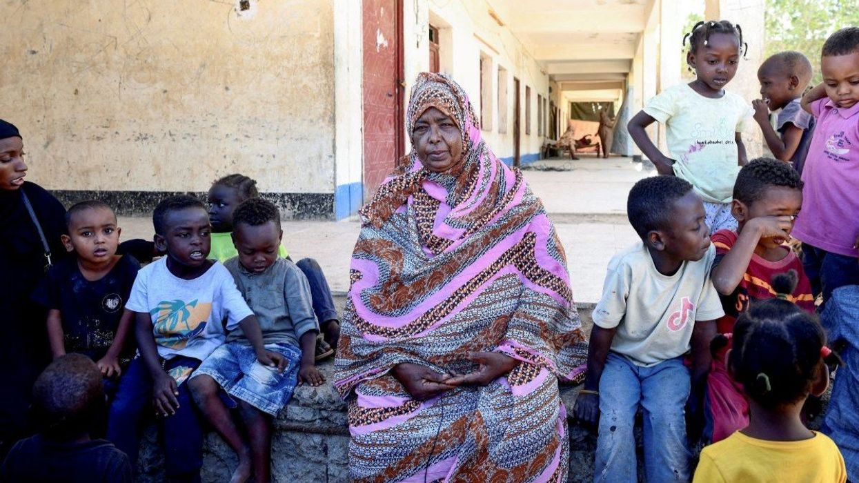 A displaced Sudanese woman looks on as she sits next children at “Abdallah Nagi” shelter camp in Port Sudan, Sudan, on April 15, 2025.