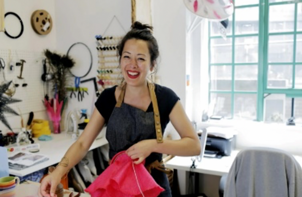 A female entrepreneur shown smiling in her shop.