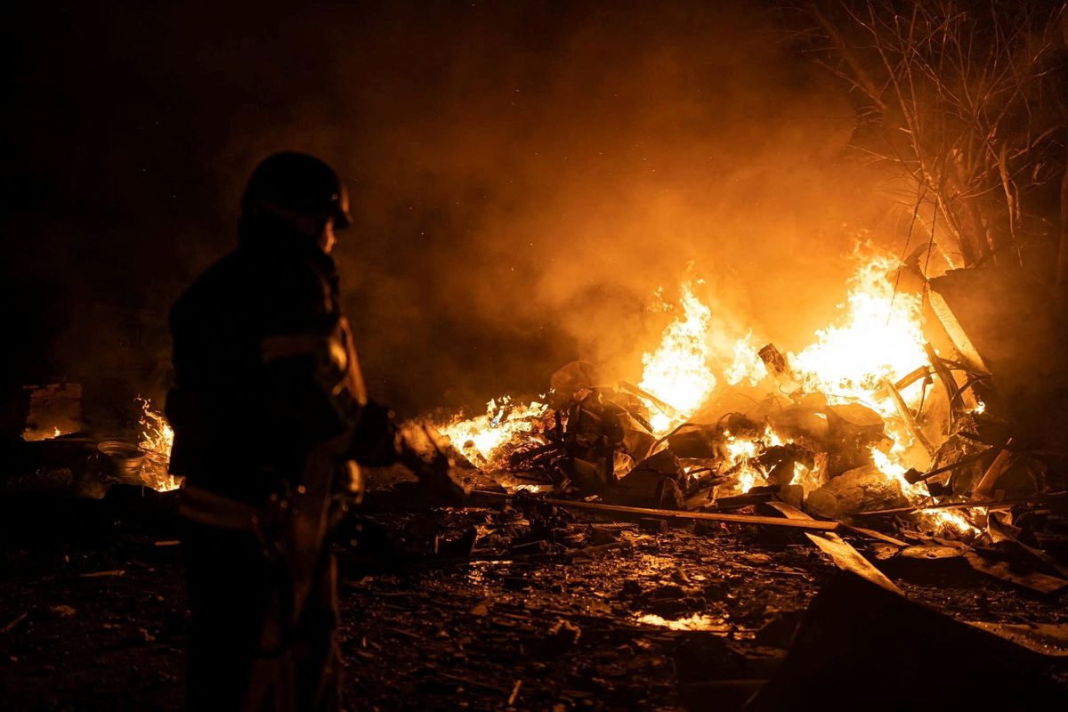 A firefighter works at a site of a vehicle parking area hit by Russian missiles in Kyiv. 