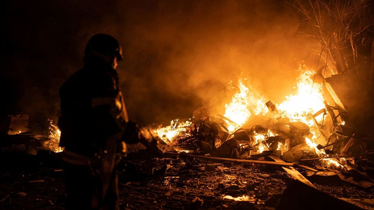 A firefighter works at a site of a vehicle parking area hit by Russian missiles in Kyiv.