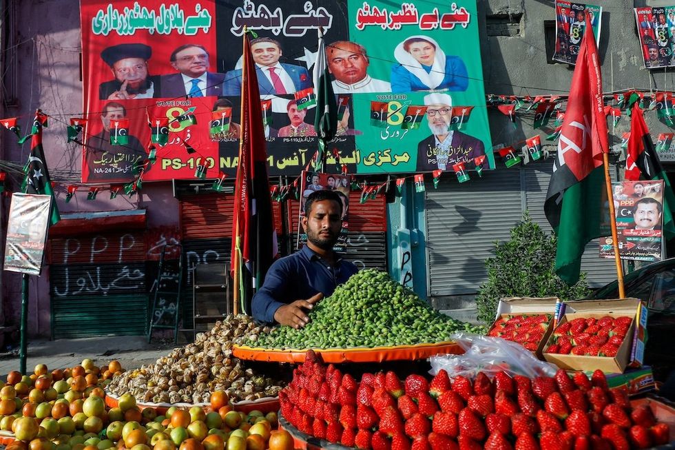 A fruit vendor waits for customers in front of campaign posters of a political party, ahead of general elections, in Karachi, Pakistan, on Feb. 1, 2024. 
