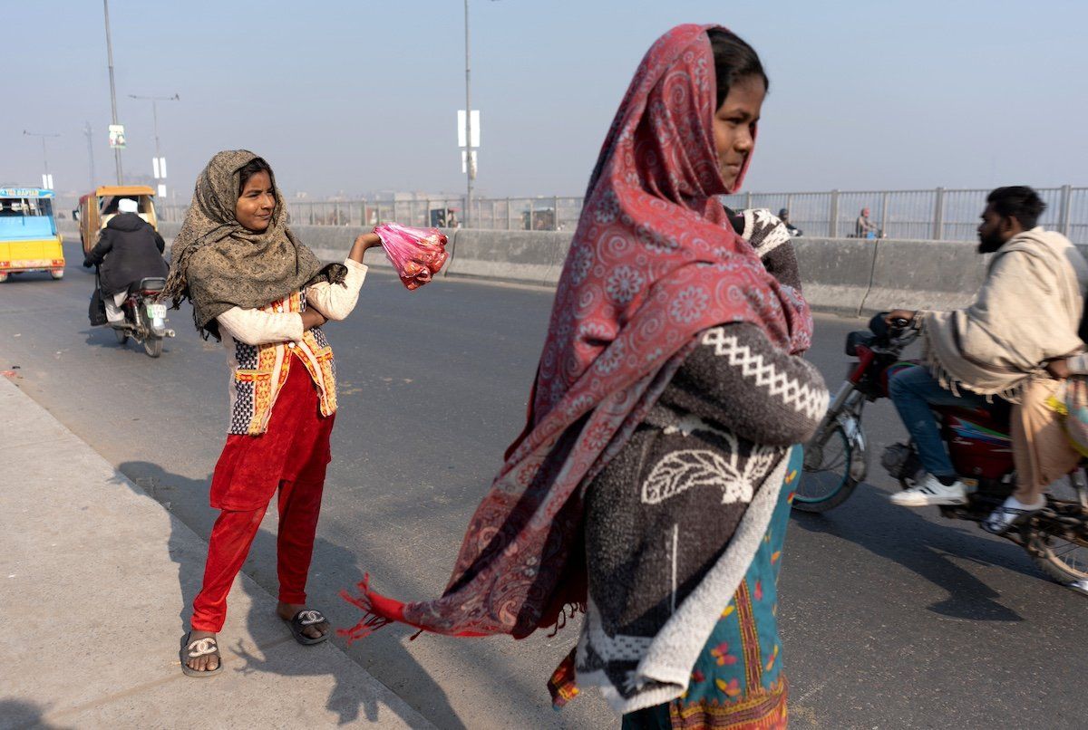 A girl waits for customers while selling meat to feed the birds, as a form of charity to bring good luck and ward off adversity, along Ravi Bridge in Lahore, Pakistan. 