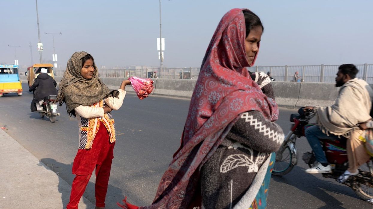 A girl waits for customers while selling meat to feed the birds, as a form of charity to bring good luck and ward off adversity, along Ravi Bridge in Lahore, Pakistan.