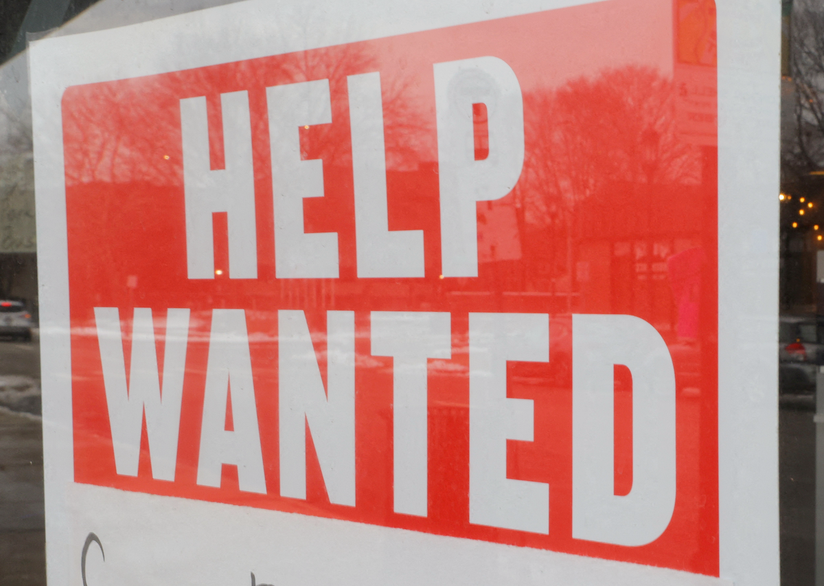 A "Help Wanted" sign hangs in a restaurant window. ​