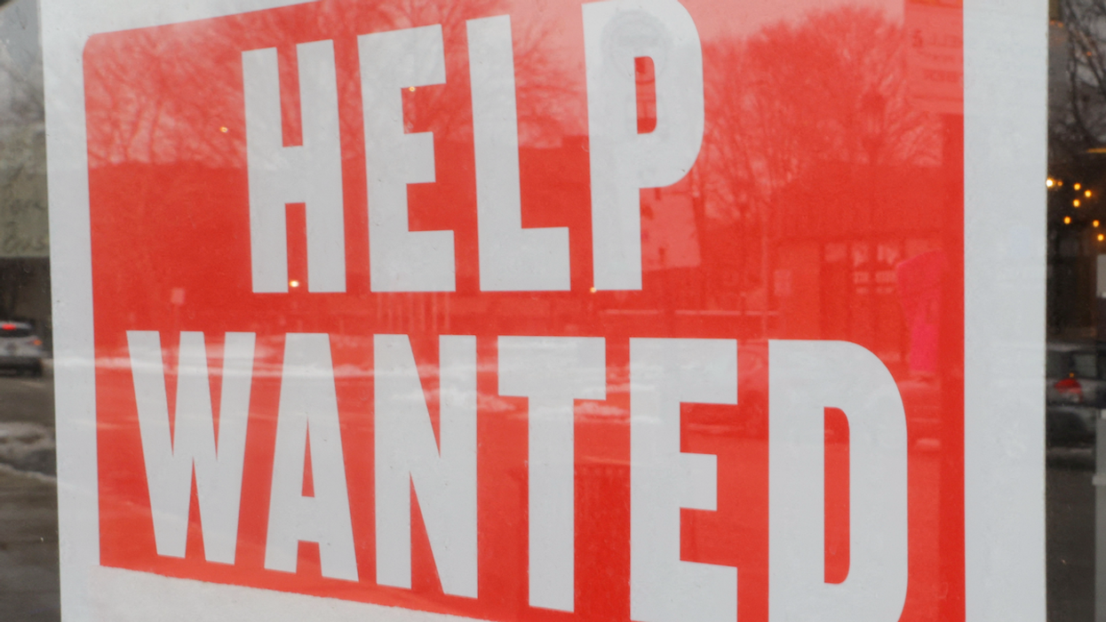A "Help Wanted" sign hangs in a restaurant window. 