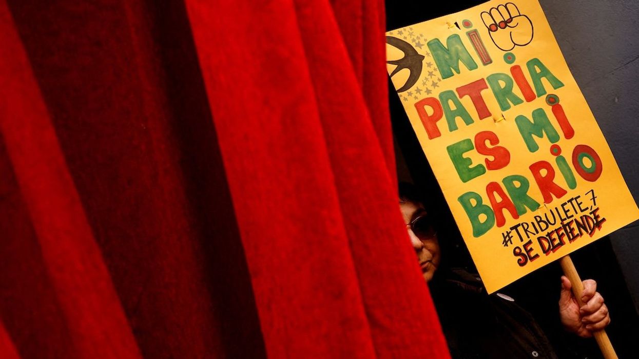 A housing activist holds a sign outside a building whose residents fear they will be evicted after its purchase by a real estate investment fund, in the neighborhood of Lavapies, in Madrid, Spain, on Dec. 14, 2024. The sign reads, "My motherland is my neighborhood."