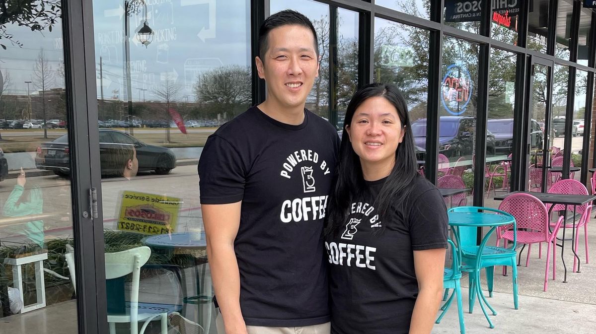 A husband-and-wife enterpreneur team standing outside their coffee shop