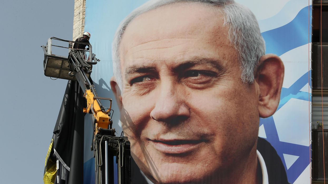 A labourer hangs a Likud party election campaign banner depicting party leader Israeli Prime Minister Benjamin Netanyahu, ahead of a March 23 ballot, in Jerusalem March 10, 2021.