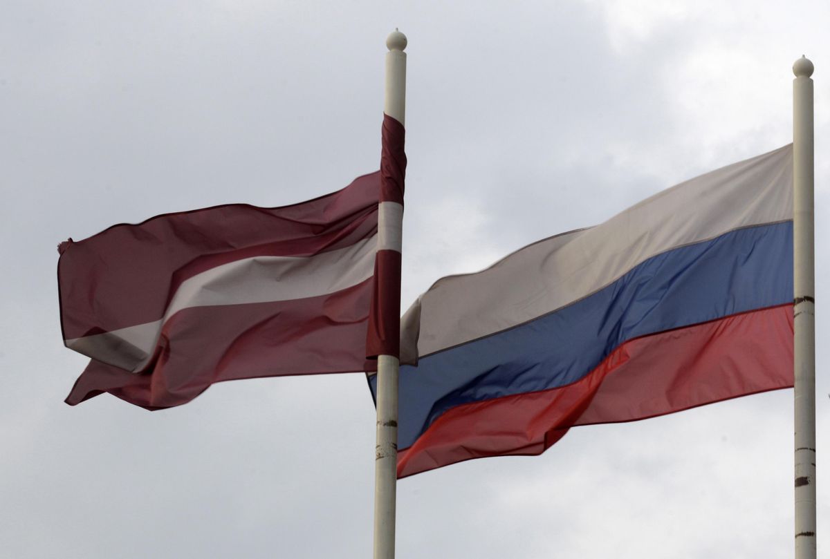 A Latvian flag flutters in the wind next to a Russian flag near a hotel in Daugavpils.