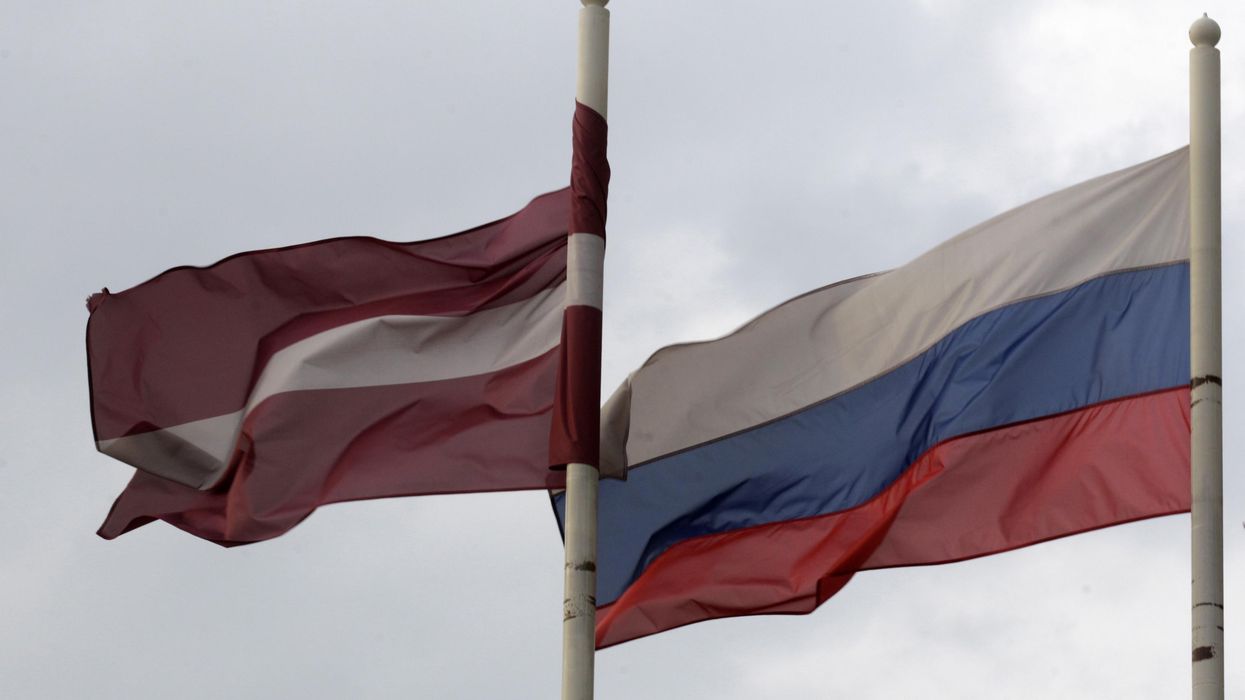 A Latvian flag flutters in the wind next to a Russian flag near a hotel in Daugavpils.