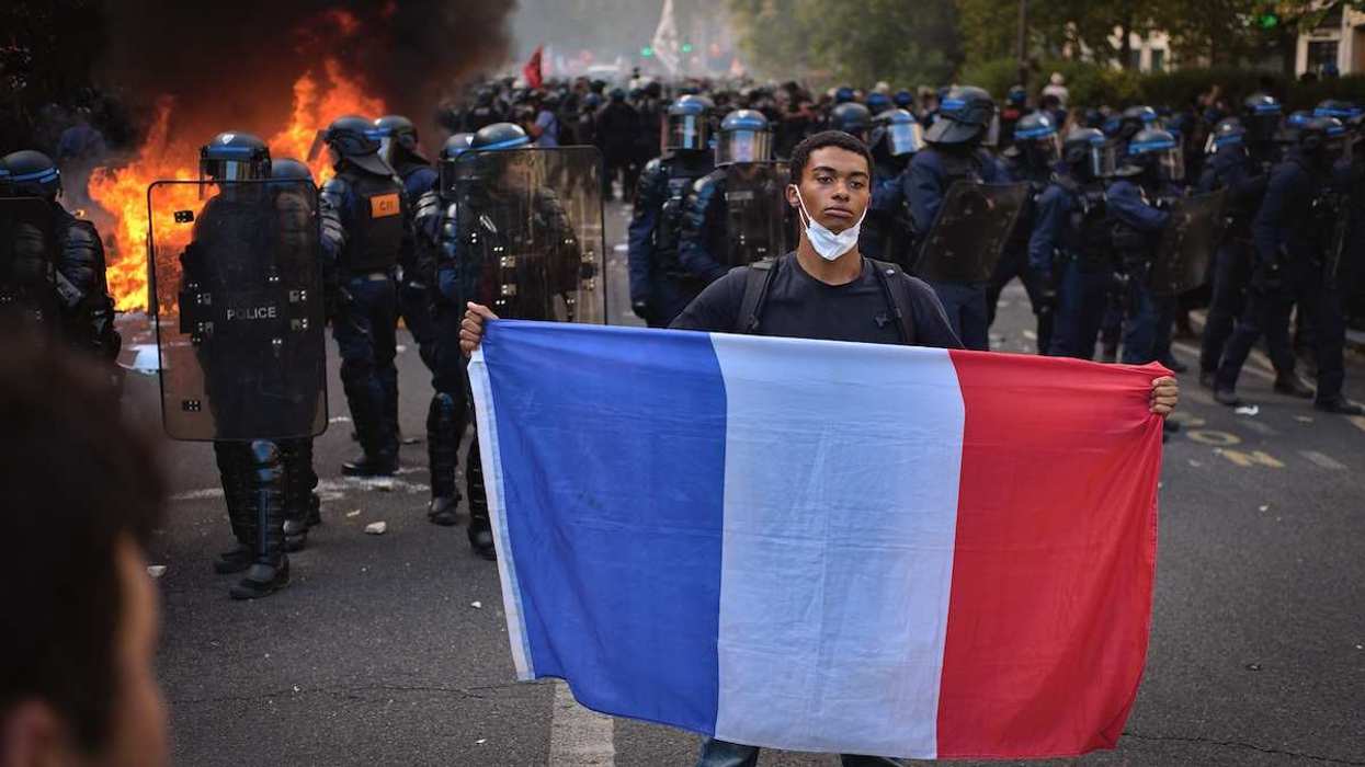 A line of riot police with protective shields faces a burning barricade as thick smoke rises in a Paris street during a high school student demonstration on October 6 2026.The scene documents the police deployment and a fire during a protest linked to public education