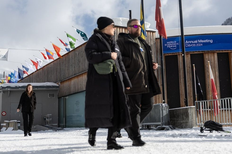 ​A man and woman walk in front of the World Economic Forum Convention Center in Davos, Switzerland.