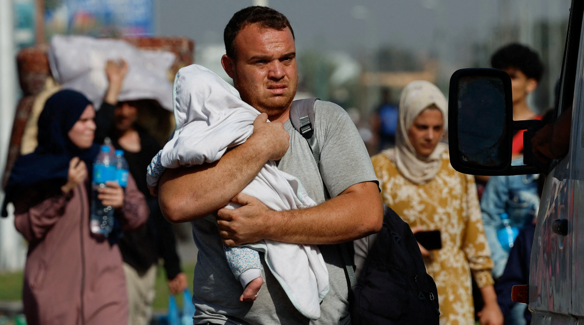 A man carries a child as Palestinians fleeing north Gaza walk towards the south, amid the ongoing conflict between Israel and Palestinian Islamist group Hamas, in the central Gaza Strip, Nov. 9, 2023.