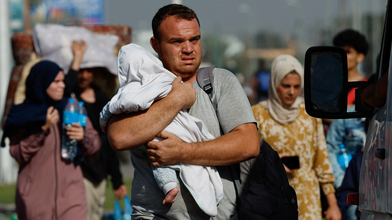 A man carries a child as Palestinians fleeing north Gaza walk towards the south, amid the ongoing conflict between Israel and Palestinian Islamist group Hamas, in the central Gaza Strip, Nov. 9, 2023.