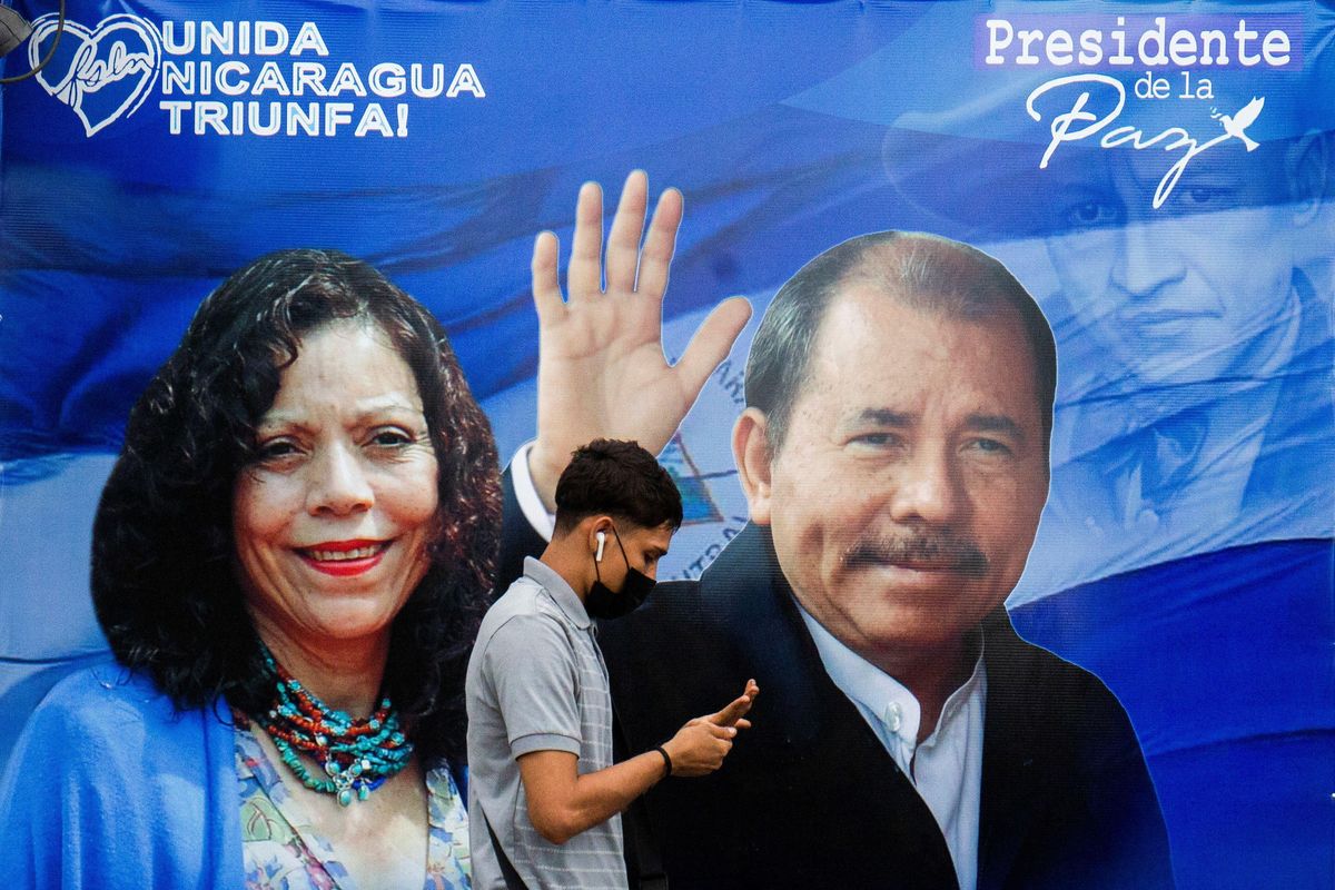 A man checks his phone while walking by a banner promoting Nicaraguan President Daniel Ortega and Vice President Rosario Murillo, as presidential election campaigns begin, in Managua, Nicaragua September 25, 2021.