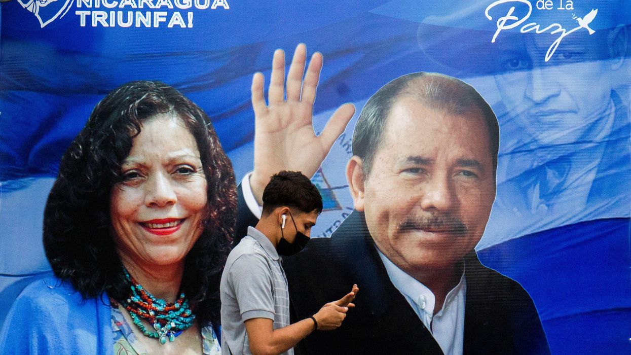 A man checks his phone while walking by a banner promoting Nicaraguan President Daniel Ortega and Vice President Rosario Murillo, as presidential election campaigns begin, in Managua, Nicaragua September 25, 2021.