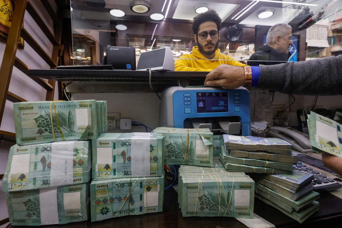 A man counts Lebanese pound banknotes at an exchange shop in Beirut, Lebanon. 