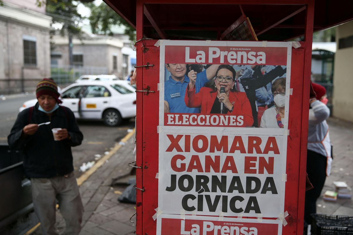 A man eats by a newspaper stand that displays a cover story on the preliminary results of the general election in Tegucigalpa, Honduras, November 29, 2021