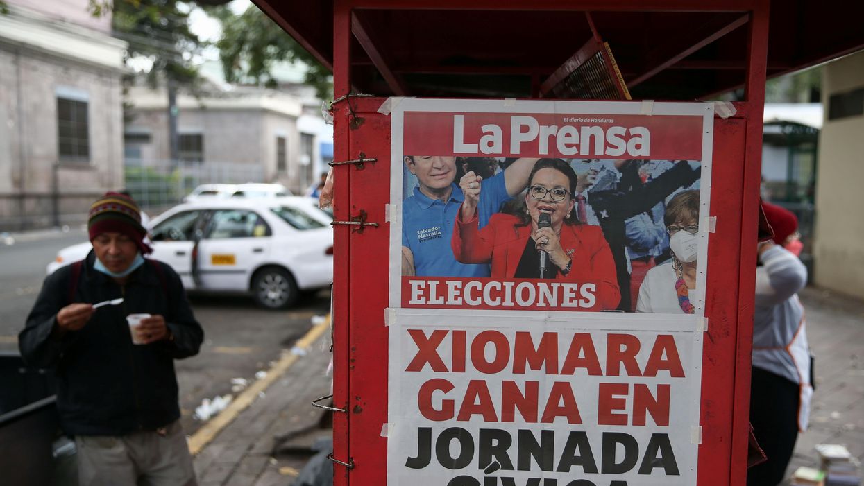 A man eats by a newspaper stand that displays a cover story on the preliminary results of the general election in Tegucigalpa, Honduras, November 29, 2021