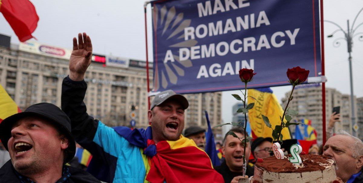 ​A man holding a cake sings Happy Birthday for Calin Georgescu during an event to celebrate Georgescu's birthday, in Bucharest, Romania, March 26, 2025. 