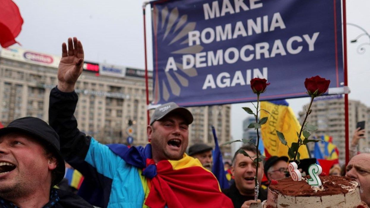 A man holding a cake sings Happy Birthday for Calin Georgescu during an event to celebrate Georgescu's birthday, in Bucharest, Romania, March 26, 2025.