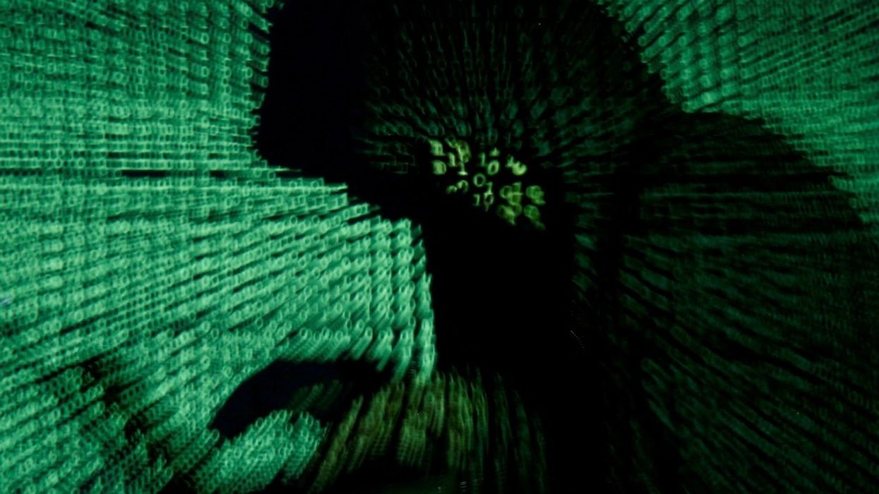 A man holds a laptop computer as cyber code is projected on him in this illustration of a hacker.