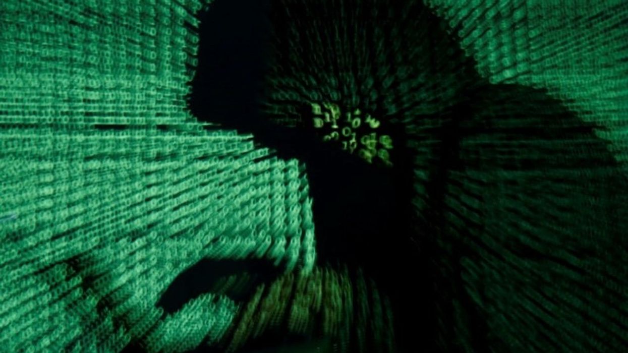 A man holds a laptop computer as cyber code is projected on him in this illustration.