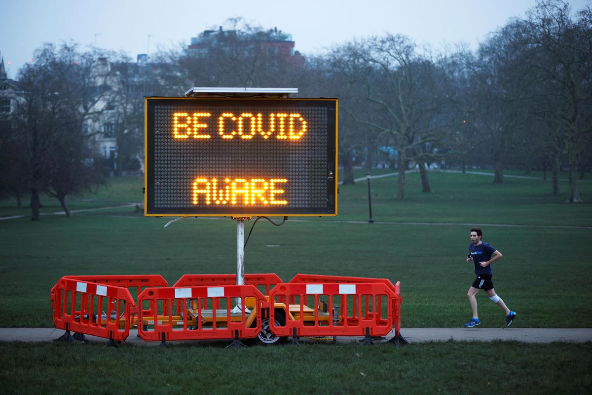 A man jogs past a public health information sign at dawn on the first day of 2021 on Primrose Hill amid the coronavirus disease (COVID-19) outbreak, in London, Britain January 1, 2021