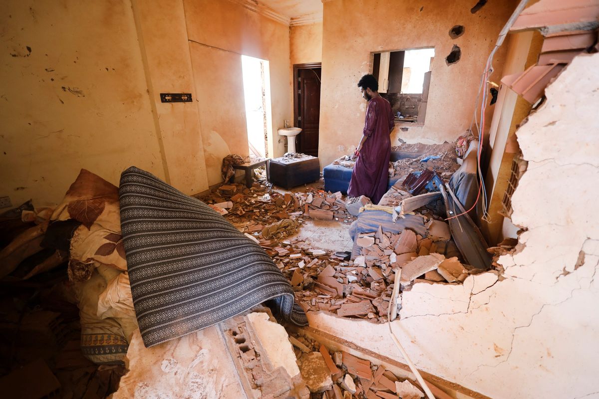 A man looks at belongings inside a damaged house during clashes between the RSF and the army in Khartoum.